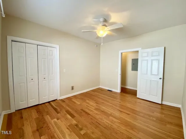a view of an empty room and chandelier fan
