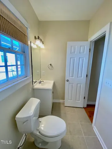 a bathroom with a toilet a sink a mirror and a window