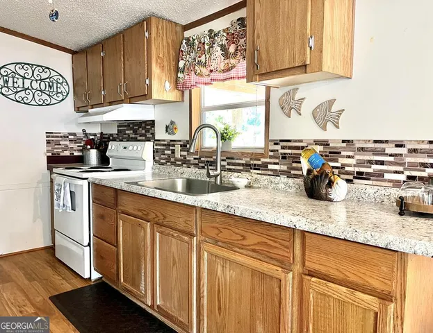 a kitchen with stainless steel appliances granite countertop a sink dishwasher stove and cabinets with wooden floor