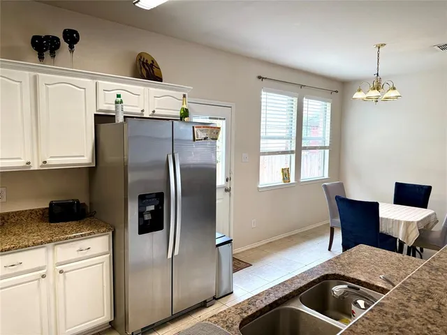 a kitchen with stainless steel appliances granite countertop a refrigerator a sink a stove and white cabinets