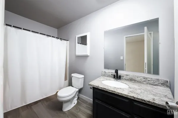 a bathroom with a granite countertop sink toilet and a mirror