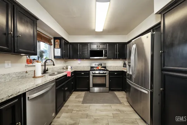 a kitchen with granite countertop stainless steel appliances and refrigerator