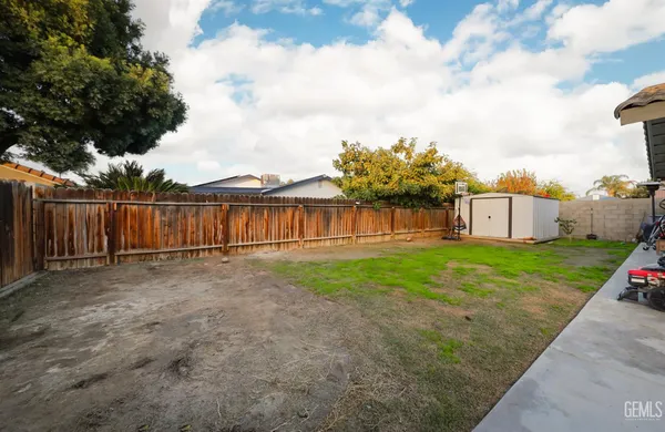 a view of a backyard with grass and wooden fence