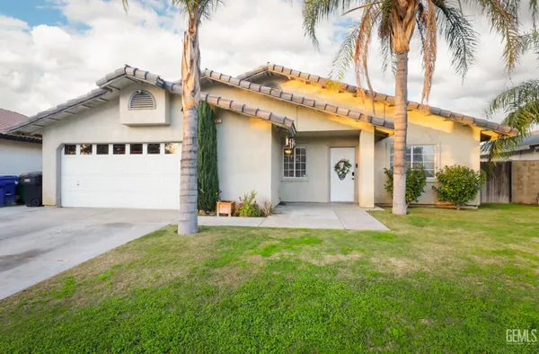 a view of a white house with a big yard and palm trees