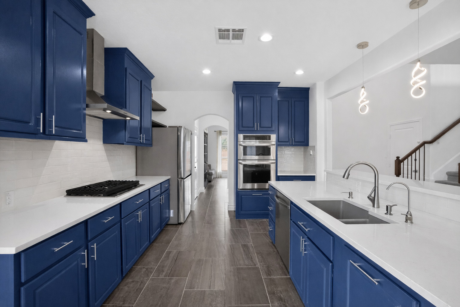 400 Cortona Lane Georgetown, TX 78628 - Photo 17 of 40 Kitchen with arched walkways, backsplash, light stone countertops, and blue cabinets