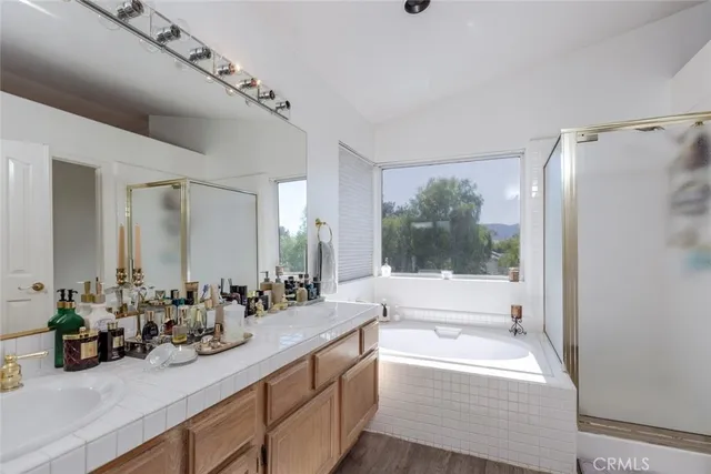 a bathroom with a double vanity sink a large mirror a bathtub and next to a window