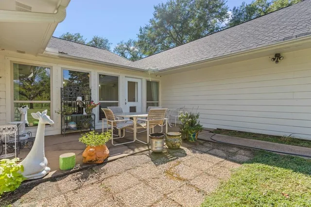 a view of a patio with table and chairs potted plants and floor to ceiling window