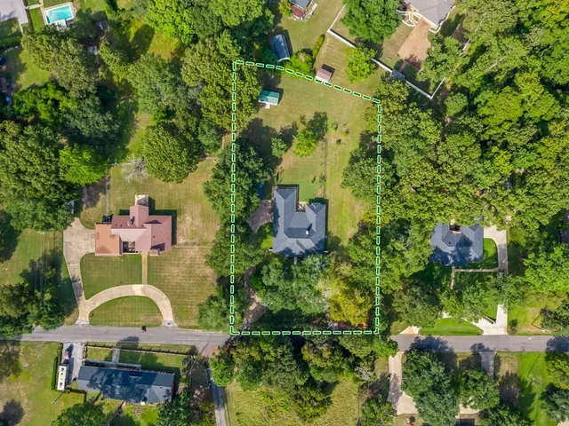 an aerial view of a house with swimming pool and large trees