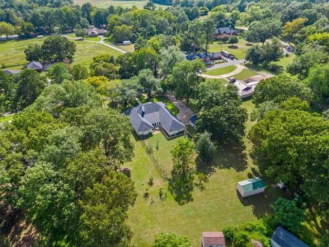 an aerial view of residential house with outdoor space and trees all around