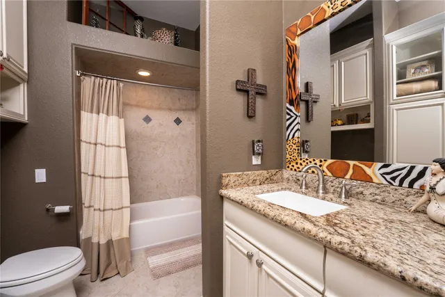 a bathroom with a granite countertop sink a toilet and shower