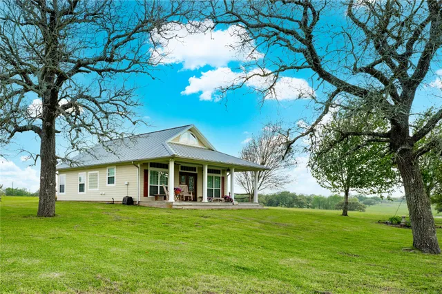 a view of a white house with a big yard and large tree