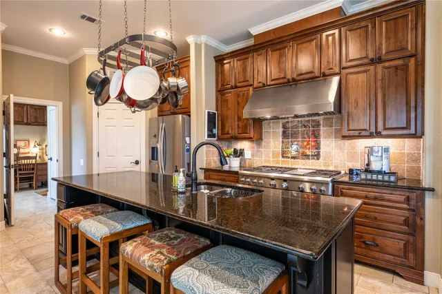 a kitchen with stainless steel appliances granite countertop a sink a stove and a wooden cabinets
