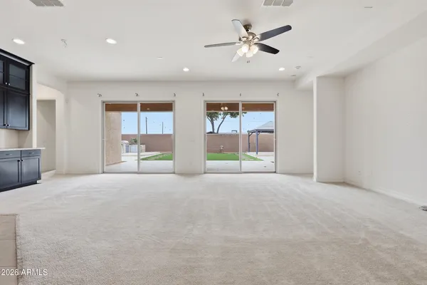 a view of an empty room with a window and a kitchen