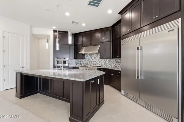 a kitchen with kitchen island granite countertop a sink and refrigerator