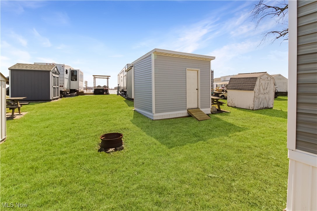 265 Meachem Road, Unit 41 Port Clinton, OH 43452 - Photo 23 of 33 View of yard featuring an outdoor structure, a fire pit, and a storage shed