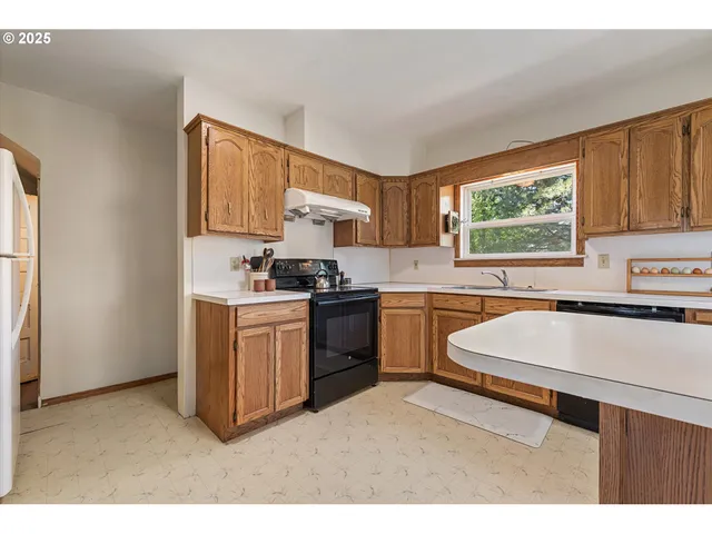 a kitchen with a sink cabinets appliances and a window