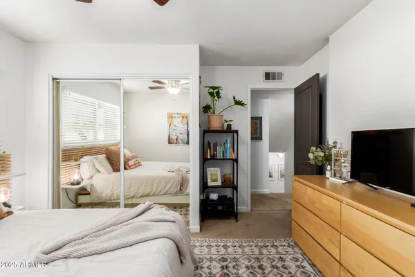 a bedroom with a bed and a flat tv screen on dresser