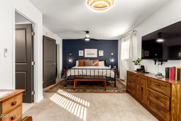 a bedroom with a bed and a flat tv screen on dresser
