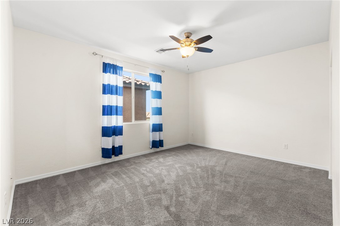 11048 Prairie Grove Road Las Vegas, NV 89179 - Photo 61 of 75 A well-lit bedroom with fresh carpet and a ceiling fan offers comfortable living.