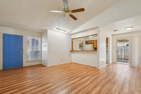 a view of empty room with wooden floor and fan