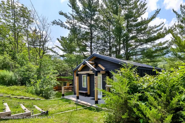 a view of a wooden house with a big yard and large trees