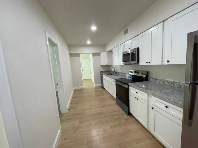 a large kitchen with cabinets stainless steel appliances a sink and a counter top space