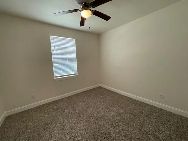 an empty room with a window and a fan