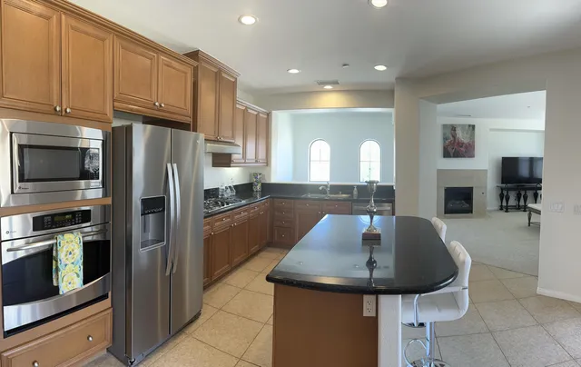 a kitchen with stainless steel appliances a sink a microwave a refrigerator and chairs
