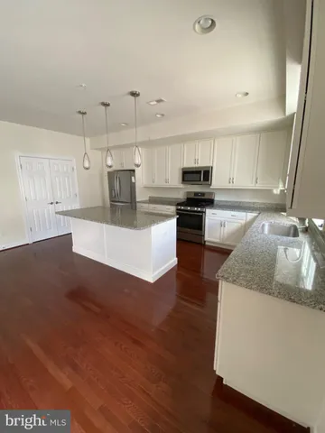 a large kitchen with stainless steel appliances granite countertop a stove a refrigerator a sink a microwave and wooden floor