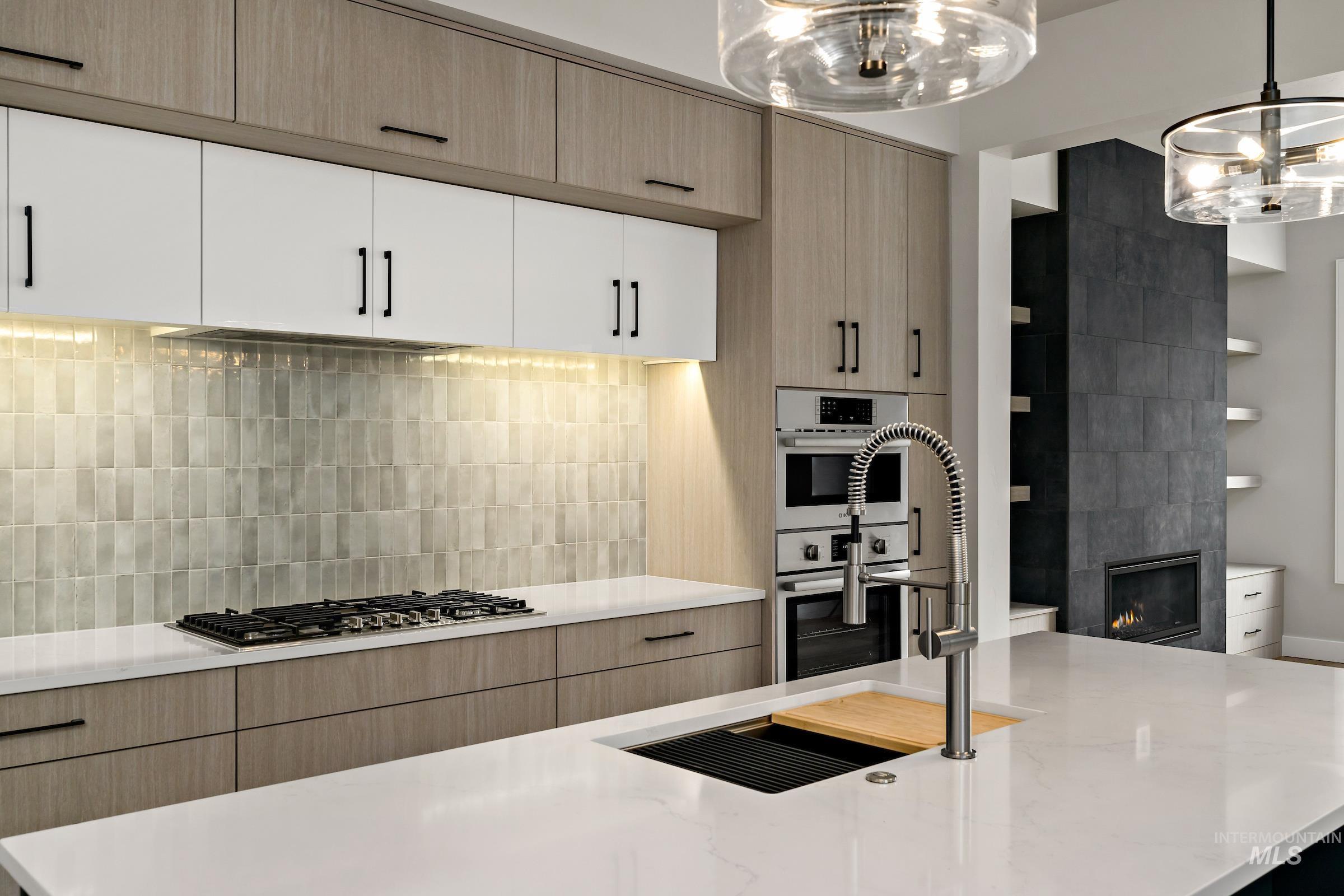 11709 North Rabbitbrush Way Boise, ID 83714 - Photo 16 of 31 Kitchen with light brown cabinets, decorative backsplash, light stone counters, and hanging light fixtures