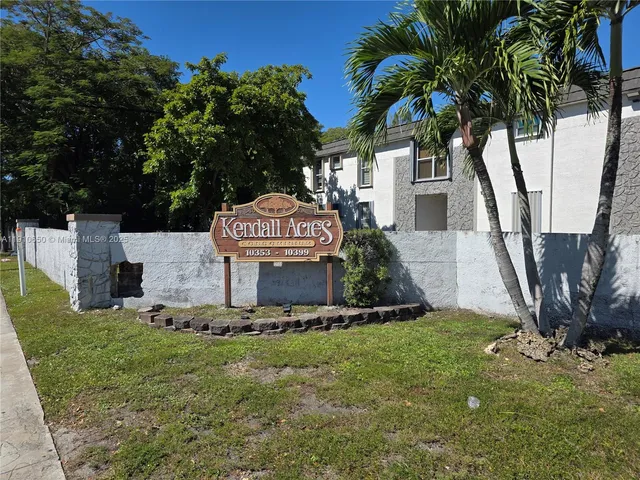 a view of a white house with a yard and potted plants