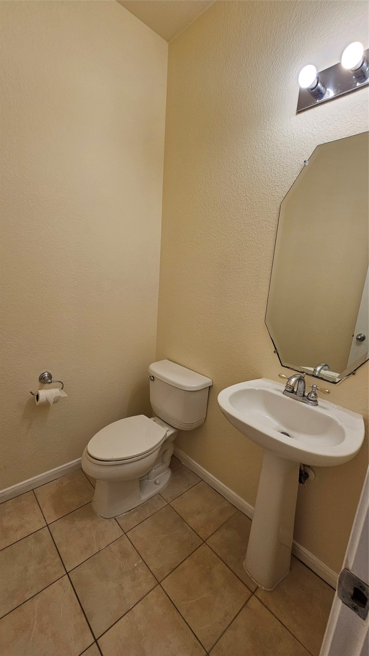7918 Barnes Ridge Lane Houston, TX 77072 - Photo 28 of 34 This is a compact half-bathroom with a pedestal sink, toilet, and wall-mounted mirror. It has a tiled floor and soft lighting, creating a clean and functional space.