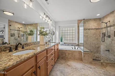 a spacious bathroom with a granite countertop tub sink shower and mirror
