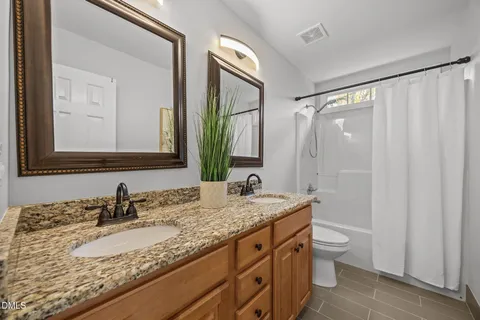 a bathroom with a granite countertop sink toilet and mirror
