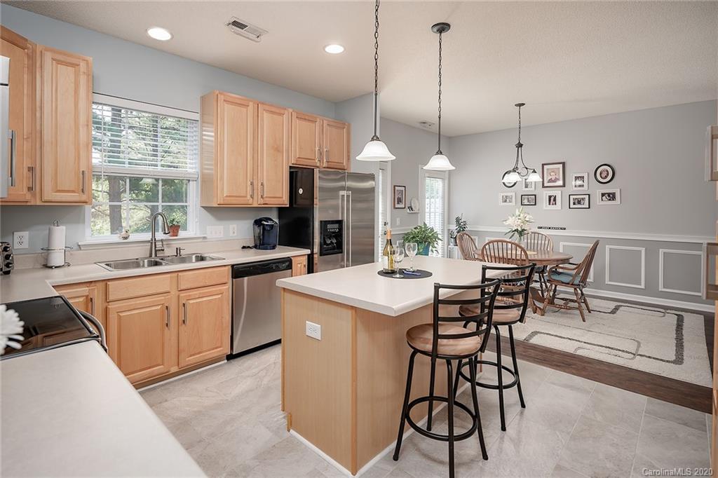 16616 Timber Crossing Road Charlotte, NC 28213 - Photo 23 of 40 a kitchen with stainless steel appliances kitchen island granite countertop a stove a sink a dining table and chairs