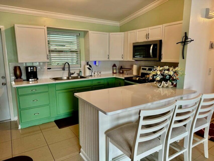 5248 Southeast 43rd Trace Okeechobee, FL 34974 - Photo 6 of 35 a kitchen with a cabinets a sink and a stove top oven with wooden floor