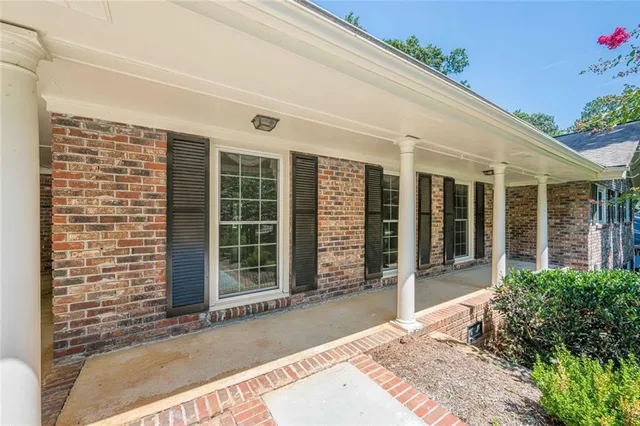 a view of an empty room with window chandelier and wooden floor