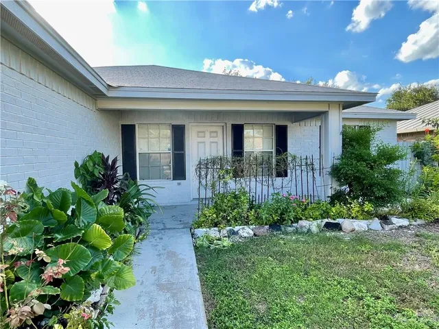 a view of a house with brick walls and a flower plants