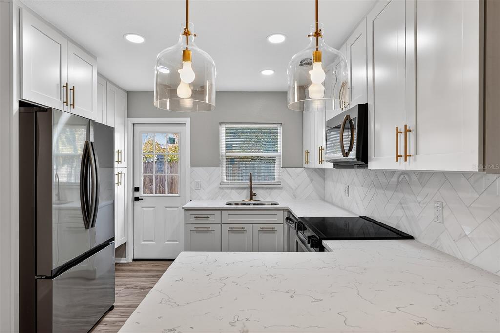 8244 125th Street Seminole, FL 33776 - Photo 5 of 32 a kitchen with stainless steel appliances kitchen island granite countertop a sink a refrigerator and a stove