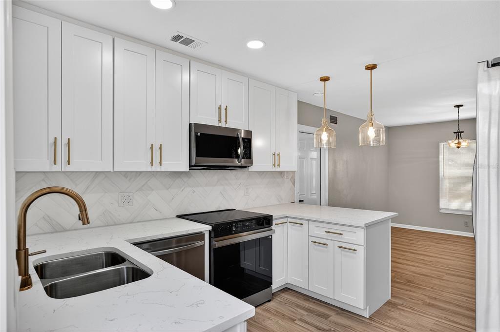 8244 125th Street Seminole, FL 33776 - Photo 7 of 32 a kitchen with stainless steel appliances kitchen island a white stove sink and cabinets