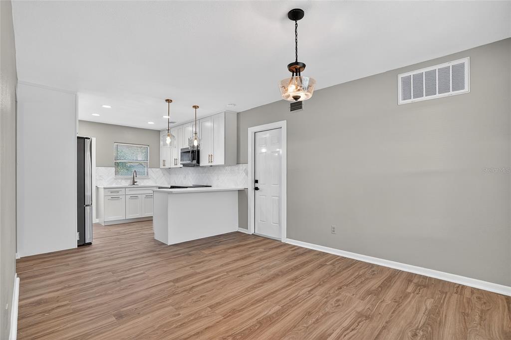 8244 125th Street Seminole, FL 33776 - Photo 9 of 32 a view of a kitchen with a refrigerator a sink dishwasher with wooden floor and cabinets