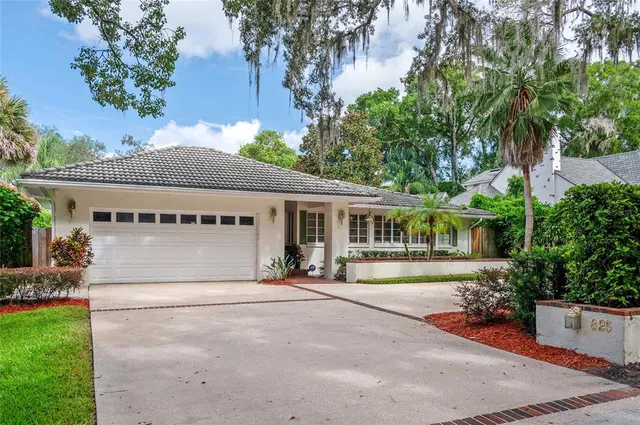 a front view of a house with a garden and trees