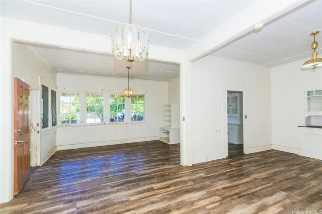 an empty room with wooden floor chandelier and entryway