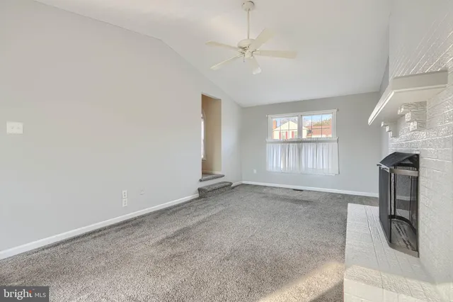 an empty room with chandelier fan and windows