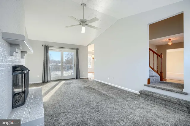 an empty room with chandelier fan and windows