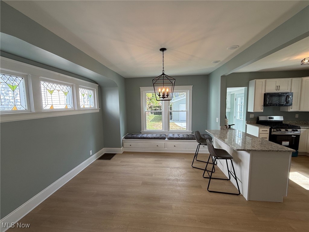 2185 Rexwood Road Cleveland, OH 44118 - Photo 5 of 26 Kitchen featuring a kitchen bar, stainless steel gas range, white cabinets, pendant lighting, and light stone counters