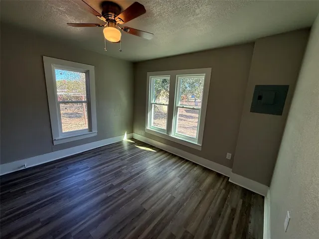an empty room with wooden floor and ceiling fan