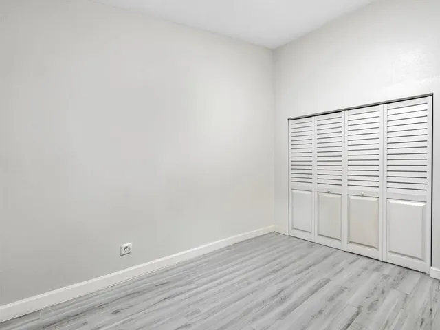 a view of an empty room with wooden floor and a ceiling fan