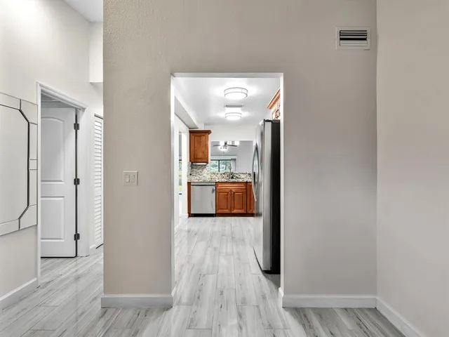 a view of a hallway with wooden floor and a living room