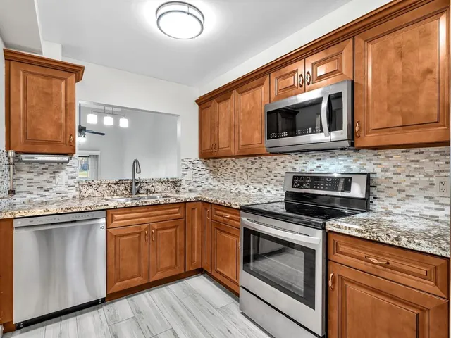 a kitchen with stainless steel appliances granite countertop wooden cabinets and a stove top oven